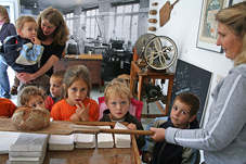 Eine Kindergartengruppe schaut zu, wie frisches Brot mit einem Holzschieber aus dem Ofen geholt wird. (Foto: Oberbergischer Kreis)