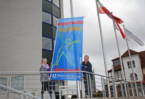 Die Gleichstellungsbeauftragte des Oberbergischen Kreises Sabine Steller und Kreismitarbeiter Jörg Braun hissen die blaue Fahne vor dem Kreishaus. (Foto: OBK)
