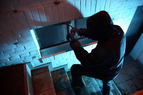 Schlecht gesichert: ein Einbrecher macht sich an einem Kellerfenster zu schaffen. (Foto: Polizei NRW)