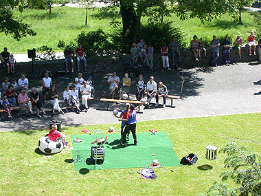 Das Bild zeigt das Treiben an dem Fussballtag auf Schloss Homburg mit Zuschauern, auf auf Bänken das Treiben verfolgen