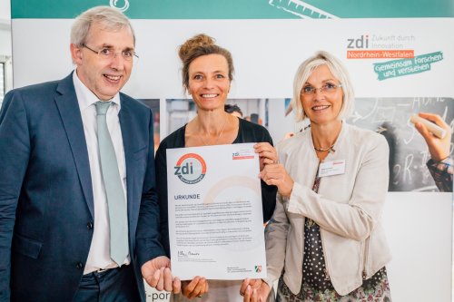 Der Parlamentarische Staatssekretär Klaus Kaiser verleiht die Urkunde an Anke Koester (r.) und Kerstin von Scheidt vom zdi-Zentrum investMINT Oberberg. (Foto: zdi NRW)