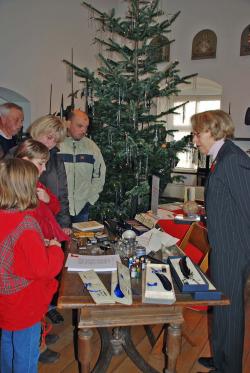 Das Foto zeigt einen Stand mit Weihnachtsschmuck und einer geschmückten Tanne im Hintergrund. (Foto: OBK) 