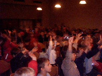 Das Foto zeigt, wie sich Kinder während der Theateraufführung durch Handzeichen am Geschehen beteiligen.