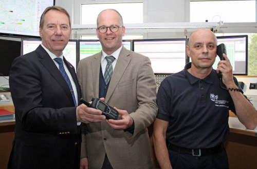 Kleines Gerät mit modernster Technik: Landrat Jochen Hagt (l.) und Bernhard Kiesecker, Leiter der Kreisleitstelle (r.) erhalten das neue Satellitentelefon von AggerEnergie-Chef Frank Röttger (Foto:OBK).