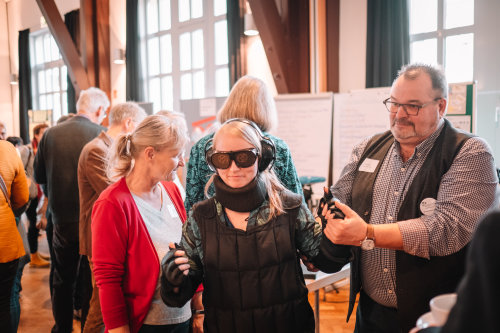Im Rahmen der Projektvorstellung „Sozialführerschein“ konnten Besucher auch den Alterssimulationsanzug GERD testen. Hier begleitet der Wiehler Lotse Wolf Lauer. (Foto: OBK)
