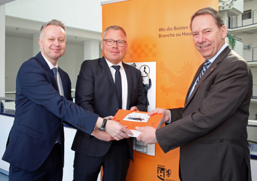 Michael Welp (Welp Druck)  übergibt gemeinsam mit Uwe Cujai (Leiter Wirtschaftsförderung OBK) Landrat Jochen Hagt das neue Standortmagazin. (Foto: OBK)