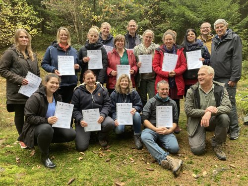 Der stellvertretende Landrat Prof. Dr. Friedrich Wilke (r.) überreichte die Zertifikate an die 13 neuen Naturerzieherinnen und Naturerzieher an ihrem zukünftigen "Arbeitsplatz" im Wald. (V.r.:) Prof. Dr. Friedrich Wilke, Christopher Jauch, Kreisjugendamt und (vorne) Dirk Nießing (Outdoor-Trainer und Ausbildungsleiter) gratulieren den erfolgreichen Absolventinnen und Absolventen. (Foto: OBK)