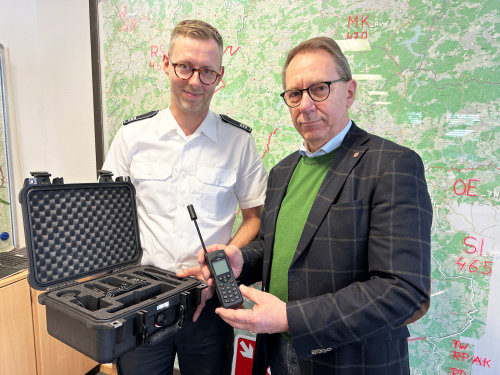 Julian Seeger (Leiter Feuer- und Rettungsleitstelle Oberbergischer Kreis, l.) und Landrat Jochen Hagt zeigen ein Satellitentelefon und das dazugehörige Equipment. (Foto: OBK)