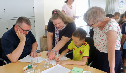 Auch Schulrat Reiner Pfesdorf (l.) und die stellvertretende Landrätin Heidrun Schmeis-Noack (r.) tüftelten mit Mathe-Sieger Matteo Nunez-Kreische und dessen Mutter an den Wettbewerbsaufgaben. (Foto: OBK) 