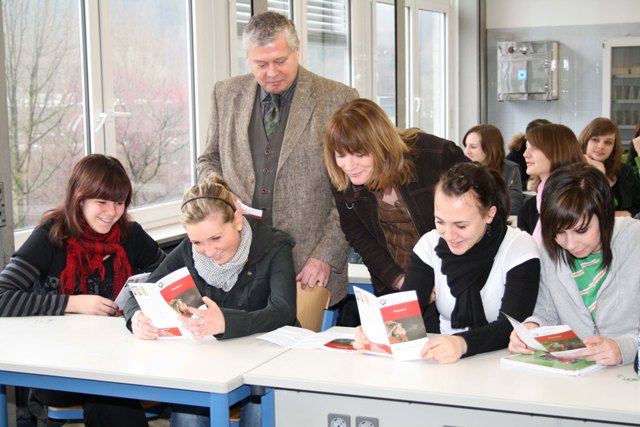 Gesundheitsdezernent Dr. Jorg Nürmberger und Gisela Hück, zuständig für Infektionsschutz, blättern mit Biologie-Schülerinnen im neuen Infoblatt über Grippe-Pandemie. (Foto: OBK)