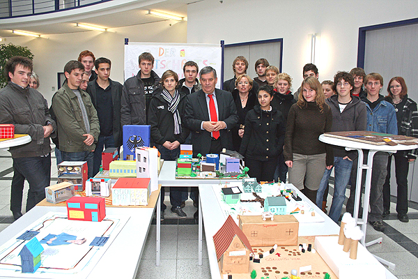 Die Ausstellungsmacher, die Stufe 12 des Gymnasiums Moltkestraße, erläuterten ihrem ersten Besucher, Landrat Hagen Jobi, die Modelle zum Thema Wirtschaftskreislauf. (Foto: OBK)