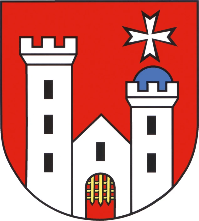 Wappen mit rotem Hintergrund, zwei weißen Türmen mit schwarzen Fenstern, dazwischen ein weißes Gebäude mit einem roten Tor und einer gelben Gitterstruktur. Oben rechts ein weißes Malteserkreuz.