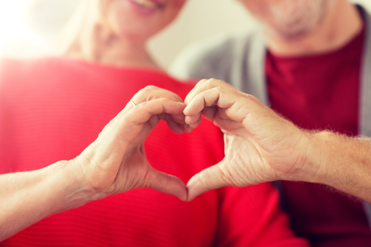 close up of senior couple showing hand heart sign