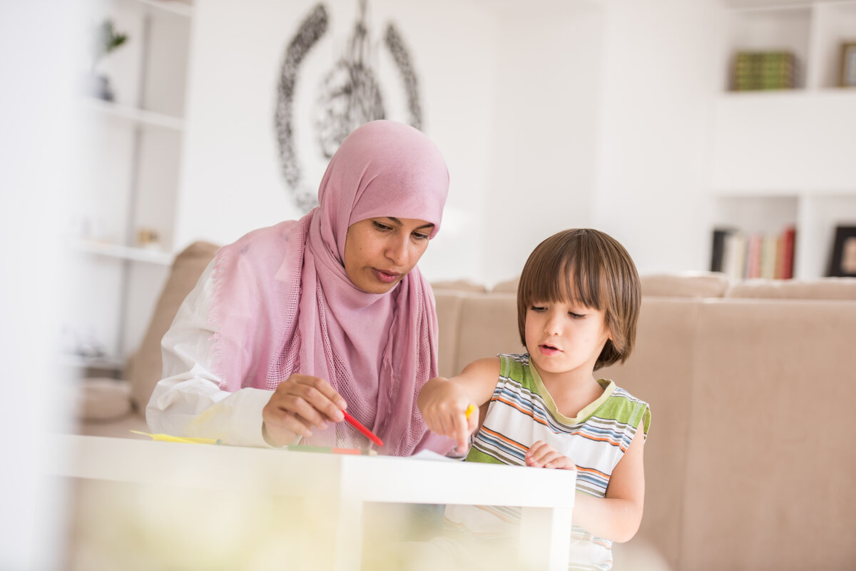 Arabic mother with little son learning in living room