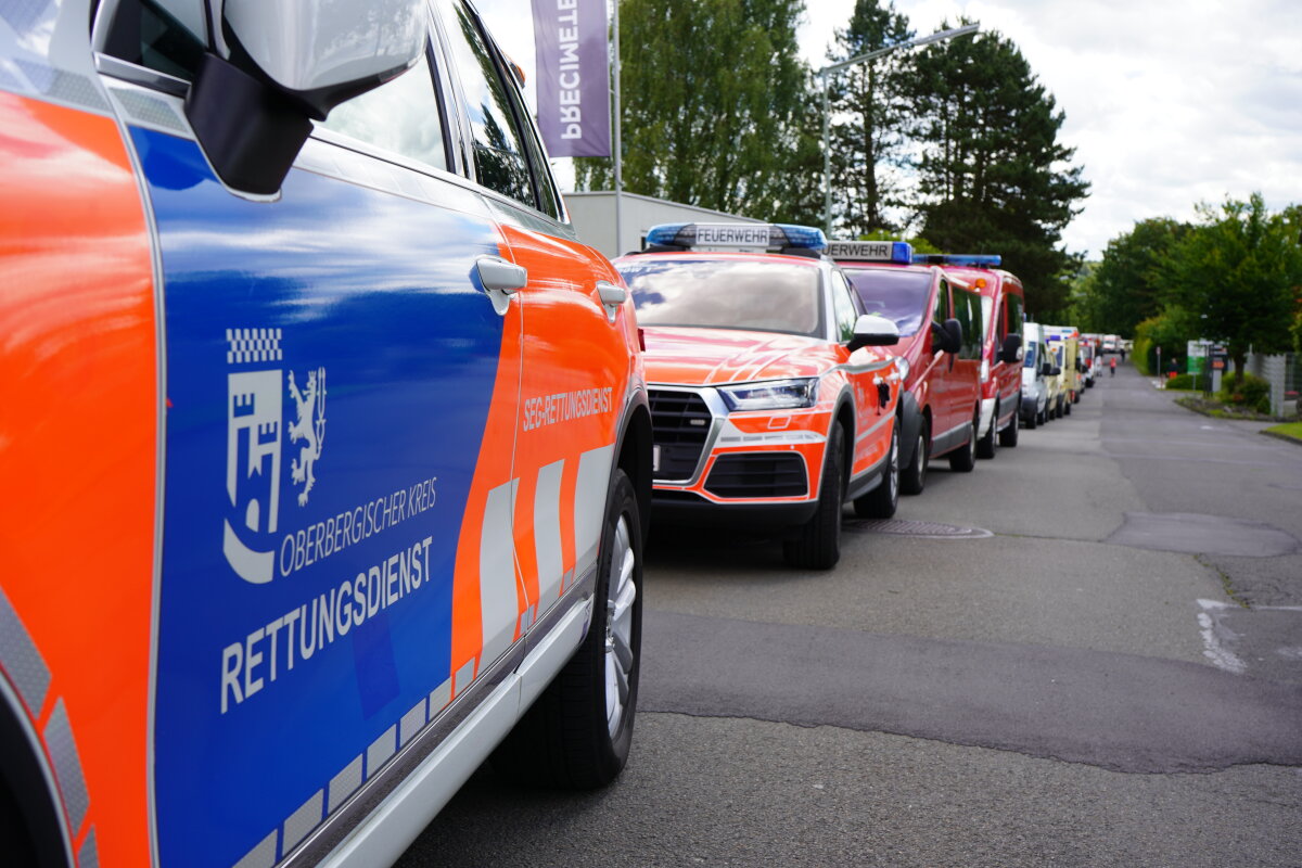 Mehrere Einsatzfahrzeuge des Rettungsdienstes und der Feuerwehr stehen hintereinander auf einer Straße. Auf dem vorderen Fahrzeug ist 'Oberbergischer Kreis Rettungsdienst' zu lesen.