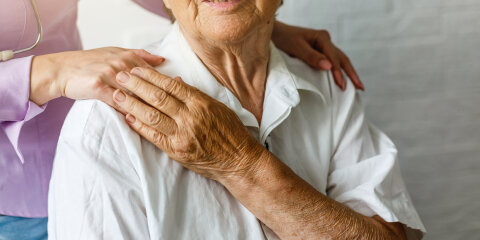 Elderly female hand holding hand of young caregiver at nursing home.Geriatric doctor or geriatrician concept. Doctor physician hand on happy elderly senior patient to comfort in hospital examination