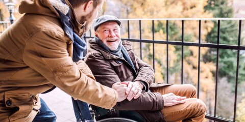 Senior father in wheelchair and young son on a walk.