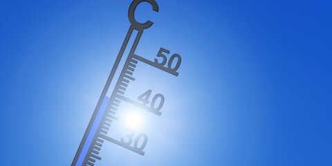 Thermometer vor Sonne am blauen Himmel