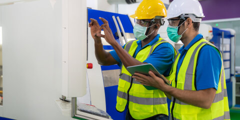 Asian industrial engineers and worker in hard hats discuss product line while using digital tablet in cnc milling cutting machine in a heavy industry manufacturing factory.