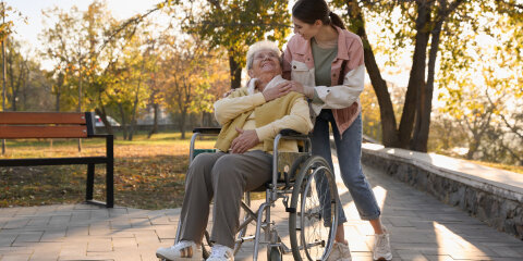 Caregiver with elderly woman in wheelchair at park