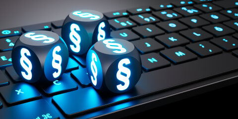 Leuchtende Würfel mit Paragraphen-Symbol auf Tastatur