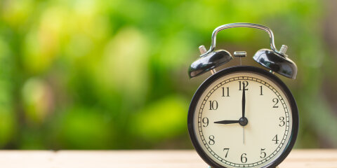 clock on wood table in the green garden time at 9 o'clock