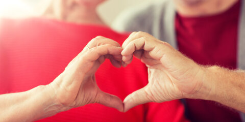close up of senior couple showing hand heart sign