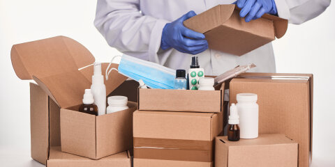 Pharmacist packing ordered medications and supplies into cardboard boxes