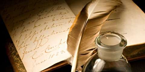 Old book with feather and inkpot