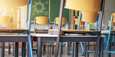 CORONAVIRUS - School closed - Empty classroom with high chairs and empty green blackboard / chalkboard with cartoon virus symbol