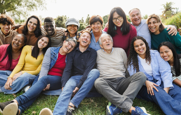 Group of multigenerational people smiling in front of camera - Multiracial friends of different ages having fun together - Main focus on senior man face