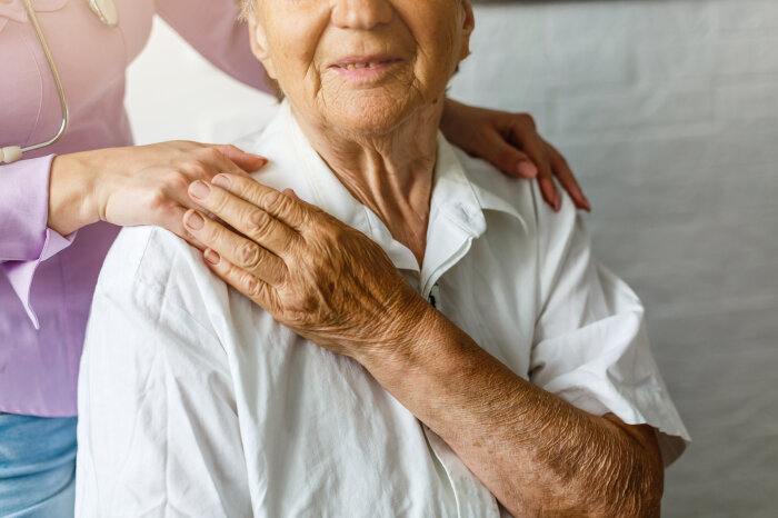 Elderly female hand holding hand of young caregiver at nursing home.Geriatric doctor or geriatrician concept. Doctor physician hand on happy elderly senior patient to comfort in hospital examination
