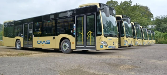 Mehrere beige Linienbusse mit der Aufschrift 'OVAG' stehen auf dem Betriebshof der OVAG. Im Hintergrund sind Bäume und Büsche zu sehen.