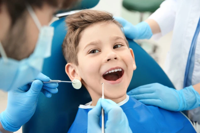 Dentist examining little boy's teeth in clinic