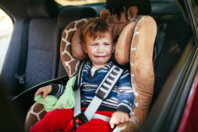 Crying baby boy in car seat.