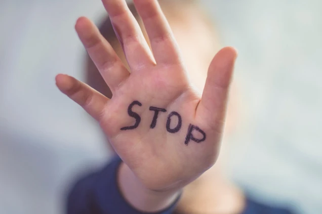 Concept of domestic violence and child abusement. A little girl shows her hand with the word STOP written on it. Children violence.
