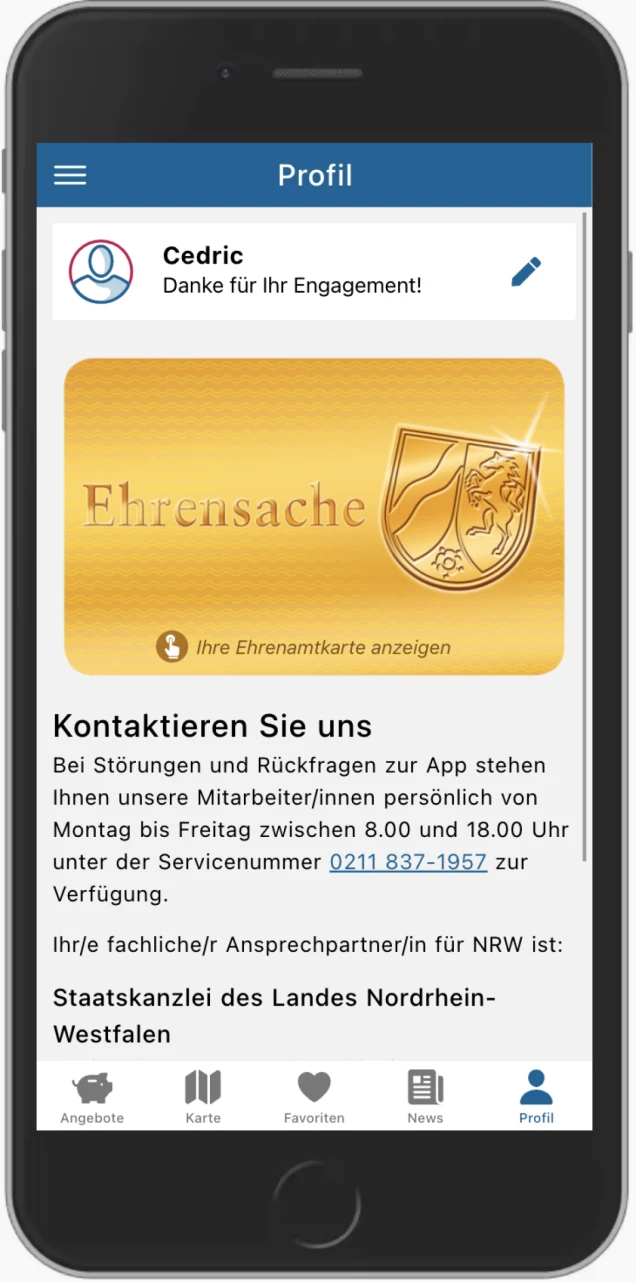 Screenshot einer App auf einem Smartphone. Der Bereich 'Profil' ist geöffnet. Oben steht 'Cedric Danke für Ihr Engagement!'. Darunter eine goldene Karte mit der Aufschrift 'Ehrensache' und einem Wappen. Text darunter bietet Kontaktinformationen und eine Telefonnummer der Staatskanzlei Nordrhein-Westfalen. Unten Menüleiste mit Symbolen: Angebote, Karte, Favoriten, News und Profil.