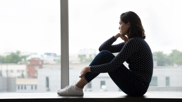 Young asian woman sit on window hug knees look away
