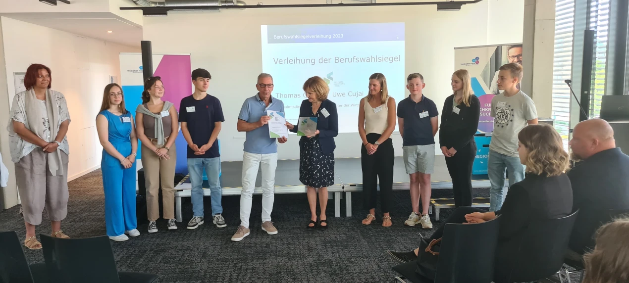Die Schulleiterin der Gesamtschule Reichshof-Eckenhagen Anne Halfar (M.) freut sich gemeinsam mit den Studien- und Berufswahlkoordinatorinnen Sabrina Becker (4. v. rechts) und Mirjam Stieber (ganz links) sowie den Schülerinnen und Schülern über die weitere Rezertifizierung.(Foto: OBK)