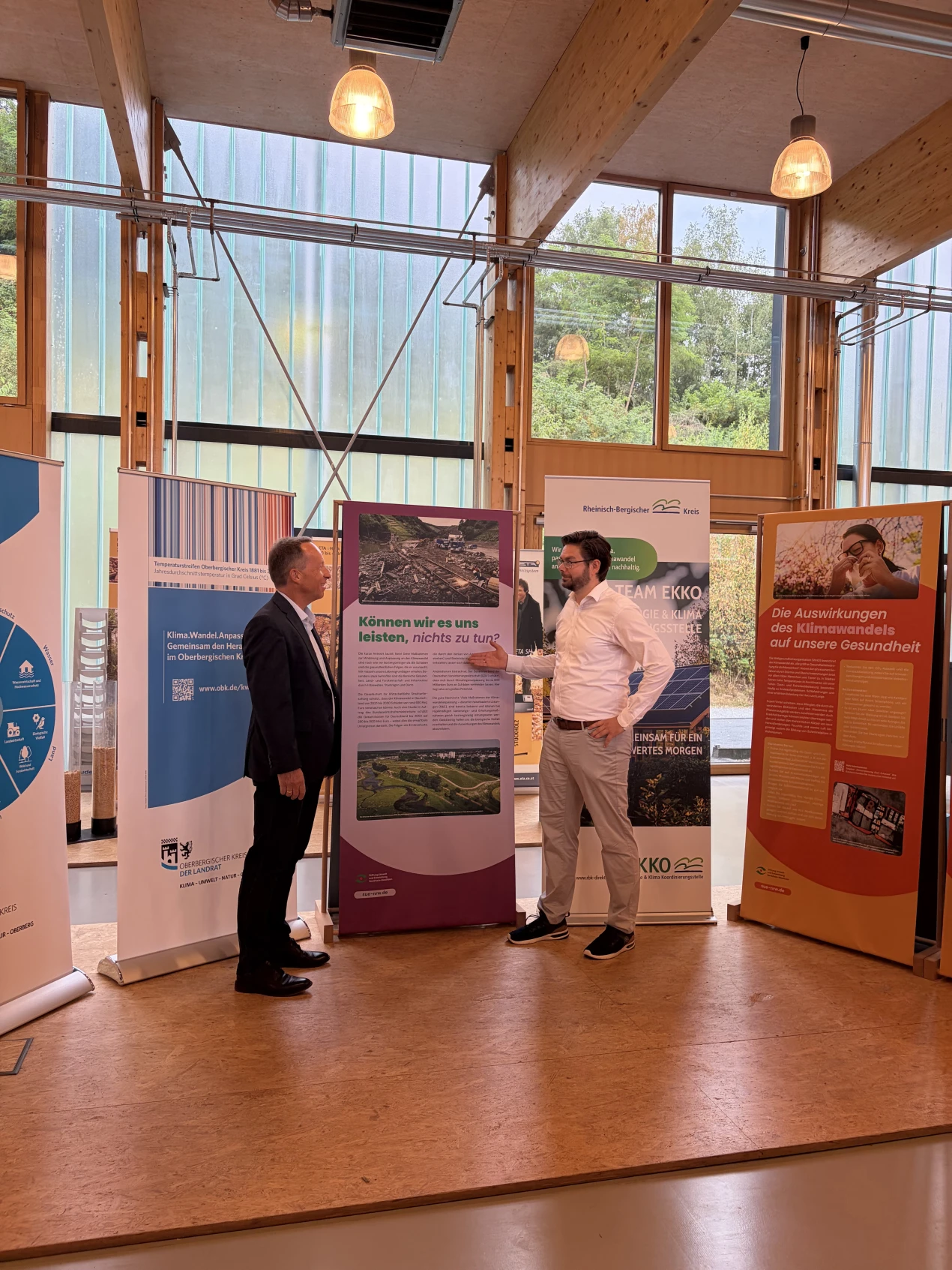 Frank Herhaus, Umweltdezernent des Oberbergischen Kreises und Heiko Krause, Umwelt- und Verkehrsdezernent des Rheinisch-Bergischen Kreises, werben für die Wanderausstellung „Klima im Wandel: wie können wir uns daran anpassen?“ auf :metabolon, in der sich Interessierte kostenfrei noch bis zum 5. August  über die Folgen des Klimawandels für ländliche Regionen sowie konkrete Beispiele zu erfolgreichen Anpassungsmaßnahmen informieren können. (Foto: Annette Göddertz) 
