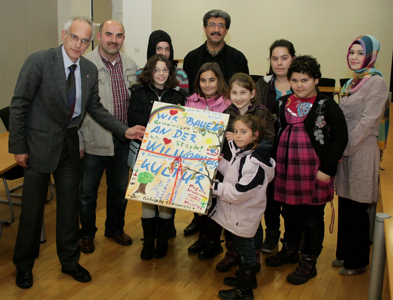 Dr. Chirstian Dickschen (1.v.l.) erhält für seine Bemühungen von Achmet Durgut (2.v.l. Vorstandsmitglied des Türkischen Elternvereins e.V. Gummersbach)ein Acrylbild der Kunst AG. (Foto: OBK)
