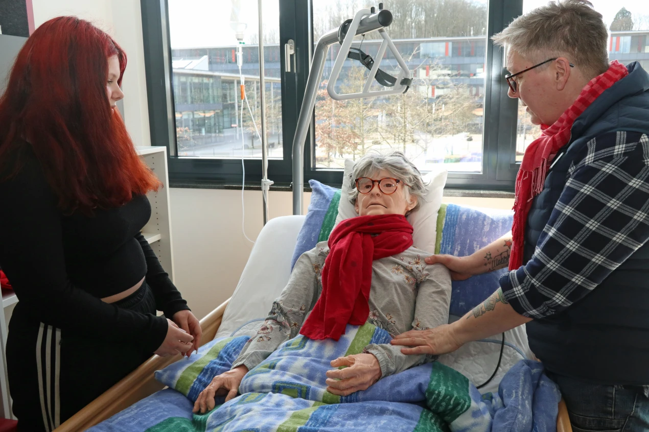 Die AGewiS vermittelt Pflege ganz praktisch: Pia Braun, Unterrichtsassistentin der AGewiS zeigt Schülerin Nele-Marie Niebel anhand einer Puppe, wie bettlägrige Menschen am besten angesprochen werden. (Foto: OBK)