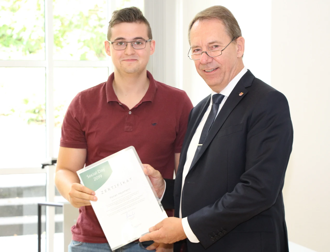 Landrat Jochen Hagt überreicht Florian Hausmann seine Social-Day-Urkunde. Er half im Familienzentrum Marie-Schlei in Bergneustadt mit. (Foto: OBK)