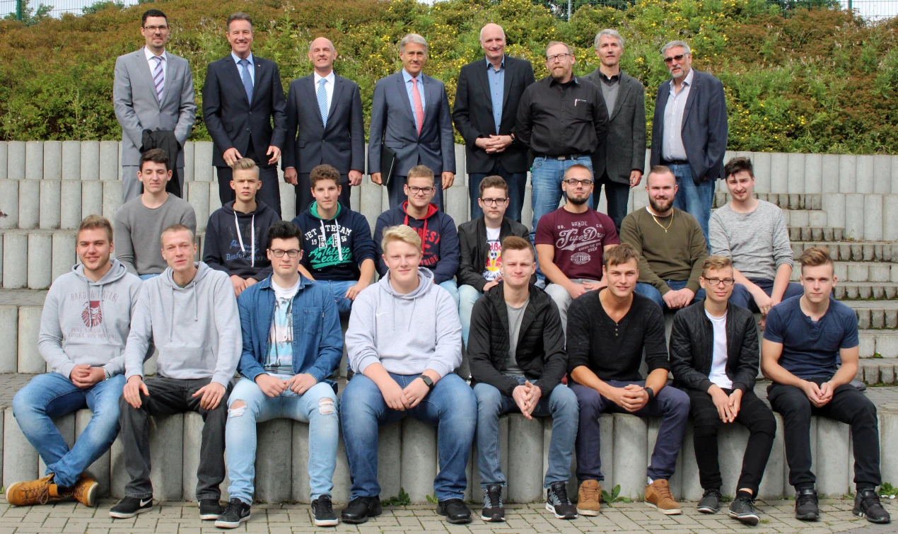 Empfingen die Berufsschüler am Standort der Gemeinschaftsschule Morsbach (Hintere Reihe, v.l.n.r.: Jörg Bukowski, Bürgermeister der Gemeinde Morsbach; Ralf Schmallenbach, Sozialdezernent des Oberbergischen Kreises; Wolfgang Bender, Geschäftsführer der Firma Montaplast; Horst Heitkamp, Personalleiter der Firma Montaplast; Michael Dietershagen, didaktischer Leiter der Gemeinschaftsschule; Markus Effenberg, Ausbildungsleiter der Firma Montaplast; Klaus Bleiweiß, Berufskolleg Dieringhausen und Jürgen Greis, Schulleiter der Gemeinschaftsschule Morsbach. (Foto: OBK) 