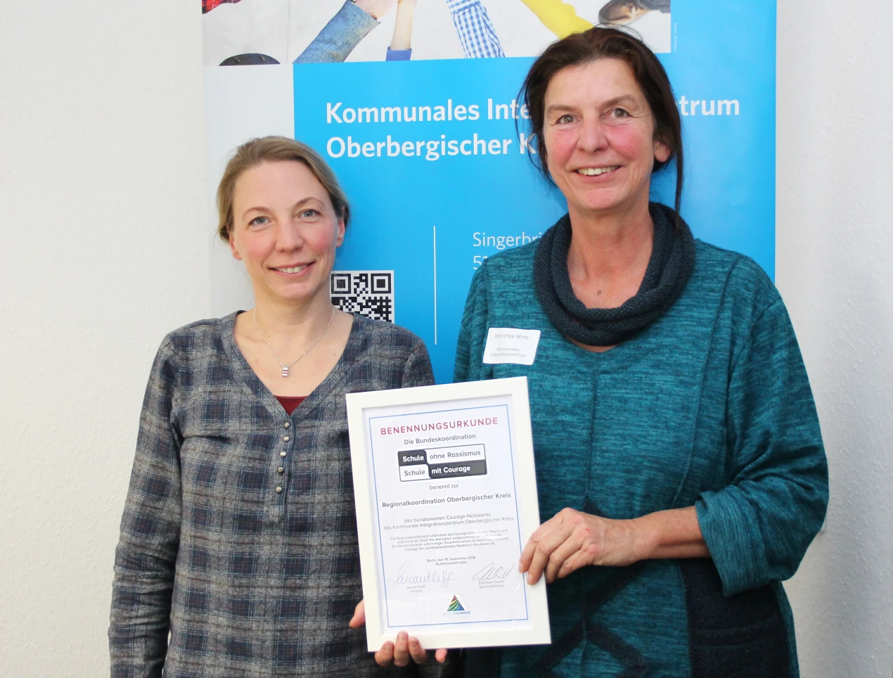 Suse Düring-Hesse (Leiterin des KI) und Dorthea Wirtz (Regionalkoordinatorin des Courage Netzwerks) mit der Benennungsurkunde für das Kommunale Integrationszentrum Oberbergischer Kreis. (Foto: OBK)
