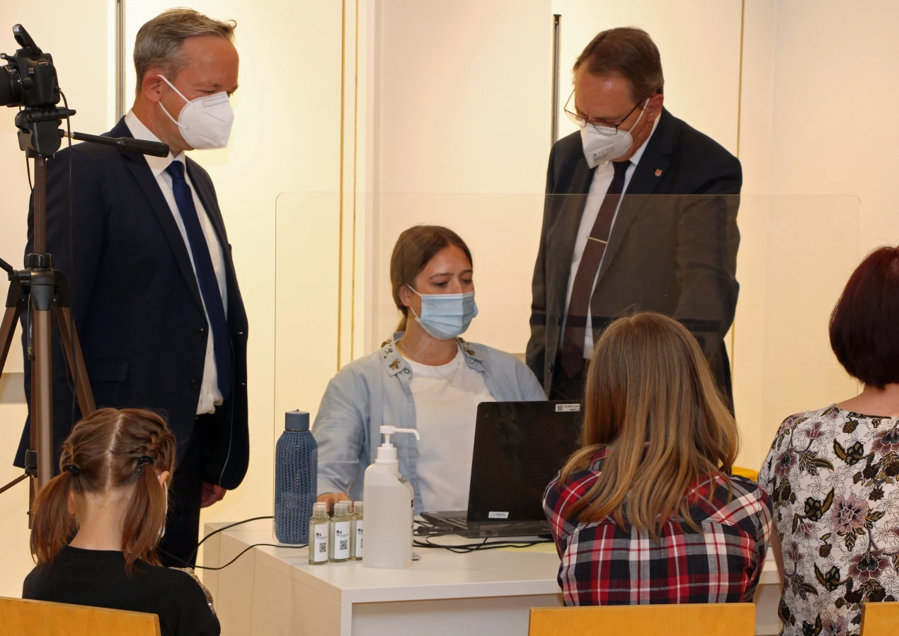 Landrat Jochen Hagt (r.) und Kreisdirektor Klaus Grootens informieren sich bei den Mitarbeitenden der Registrierungsstelle über den bisherigen Verlauf der Registrierungen und Untersuchungen. (Foto: OBK)
