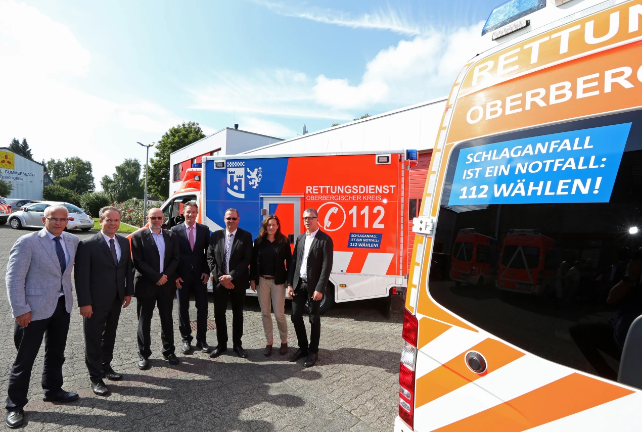 Die Initiative Oberberg gegen den Schlaganfall wirbt auf den Rettungsfahrzeugen mit großen Stickern für schnelles Handeln im Notfall (v.l.n.r.): Dr. Christian Dickschen, Dezernent Rettungsdienst; Kreisdirektor Klaus Grootens; Prof. Dr. Franz Blaes; Ralf Schmallenbach, Gesundheitsdezernent; Andreas Hüpper, AOK Rheinland-Hamburg/ Regionaldirektion Oberberg, Rhein-Berg, Leverkusen; Kathrin Duve, Reha-Expertin und Selbsthilfe-Beauftragte der Dr. Becker Rhein-Sieg-Klinik in Nümbrecht und Dr. Jürgen Bonnert, Chefarzt der Fachklinik Neurologie am MediClin Rehazentrum Reichshof. (Foto: OBK)