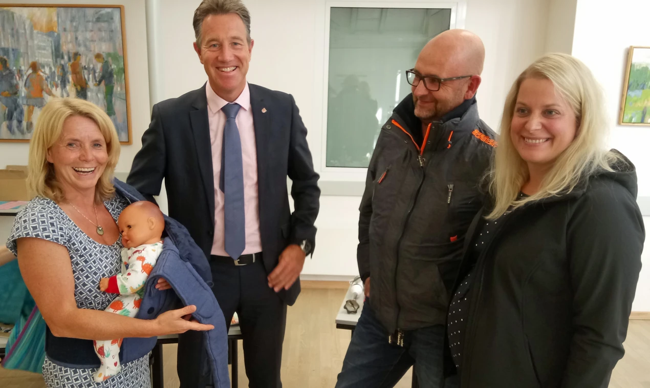 Familienhebamme Bettina Bremer (l.) zeigt Sozialdezernent Ralf Schmallenbach (M.) und Besuchern, wie man eine Babytrage richtig anlegt. (Foto: OBK)