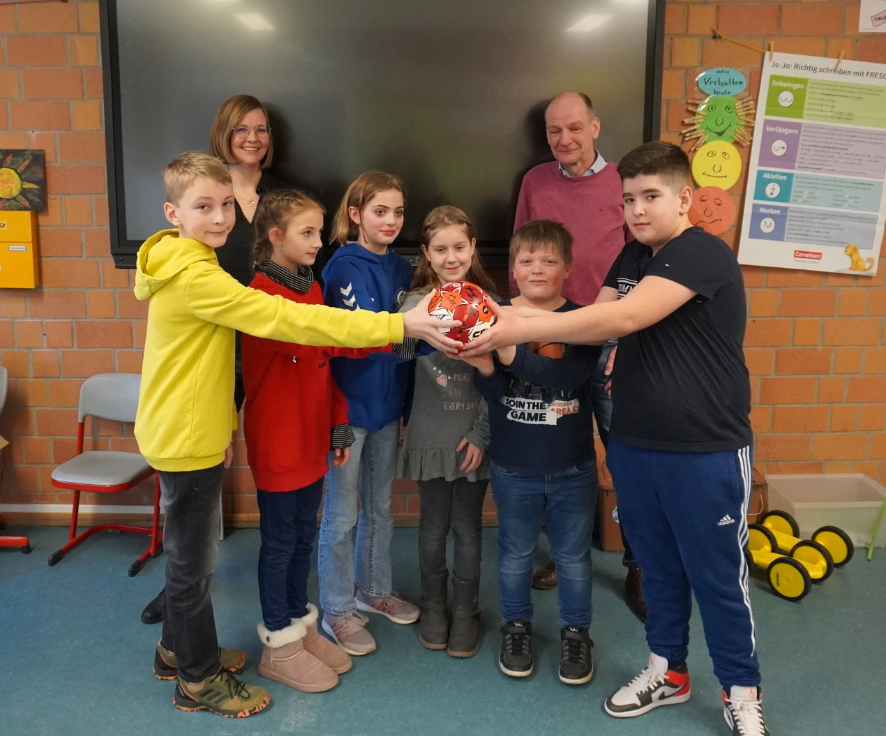 Ganz begeistert von dem signierten Handball des VfL Gummersbach, den Norbert Fischer (Bildungsbüro Oberberg) überreicht hat: Schulleiterin Jessica Schudt (l.) und Schülerinnen und Schüler der Gemeinschaftsgrundschule Becke. (Foto: OBK)