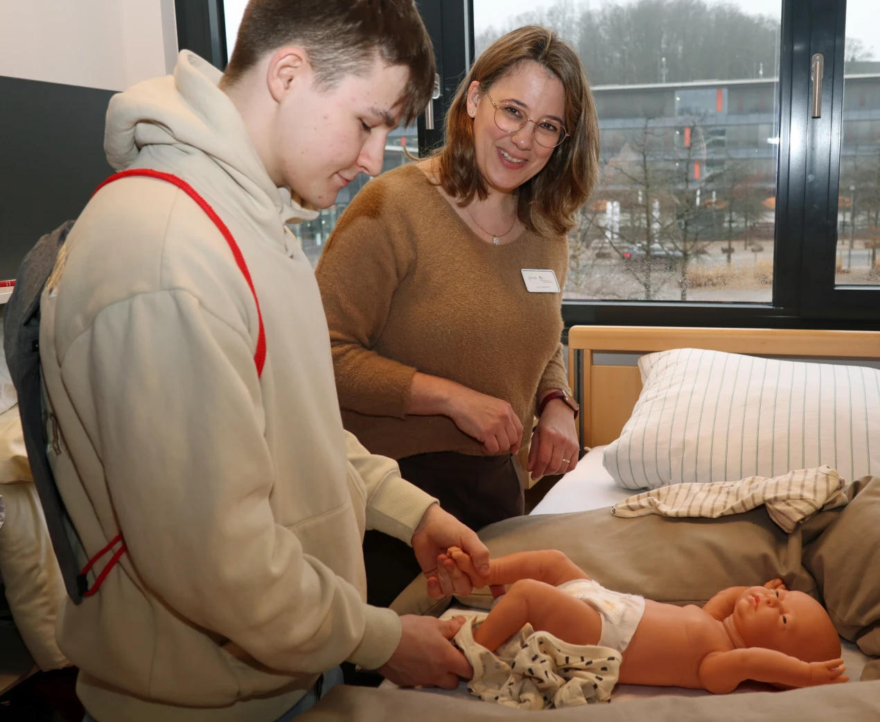 Der 18-jährige Berufsschüler Kai lernte anhand einer Babypuppe, wie Kinder gewickelt werden. Vera Hollaender, pädagogische Mitarbeiterin der AGewiS, gab Tipps. (Foto: OBK)